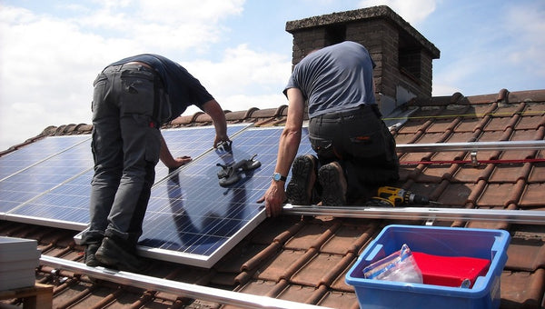 operarios instalando placas solares en el tejado de una casa
