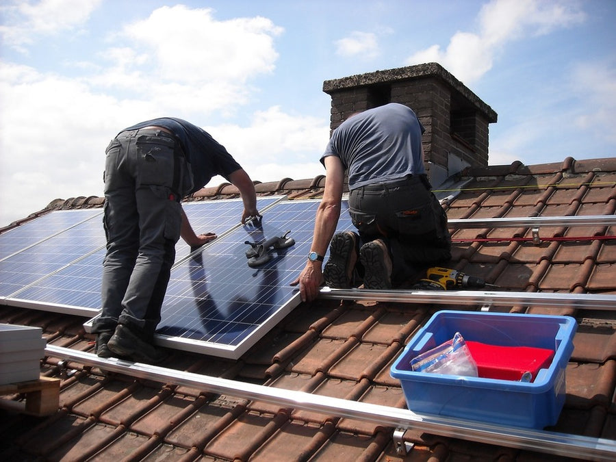 operarios instalando placas solares en el tejado de una casa